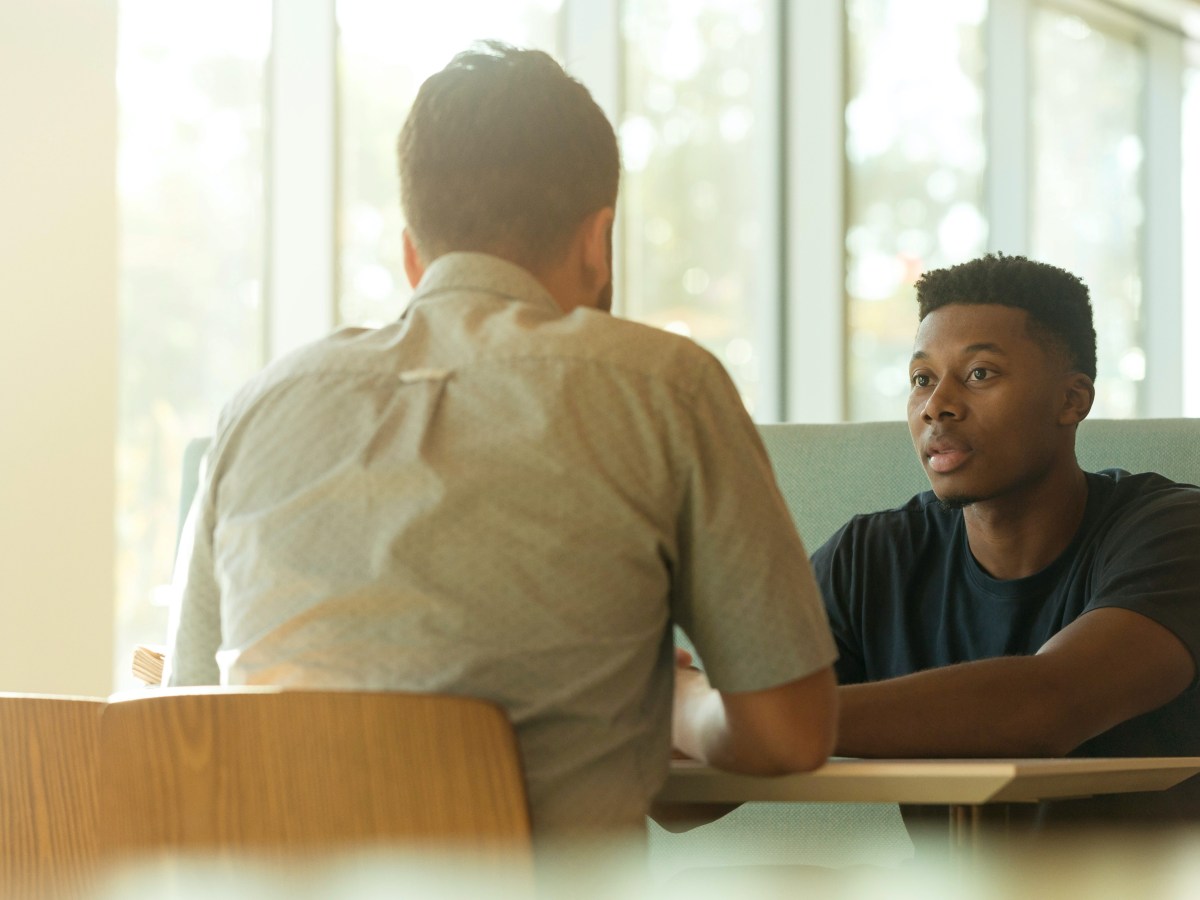 Two men sit at a table facing each other