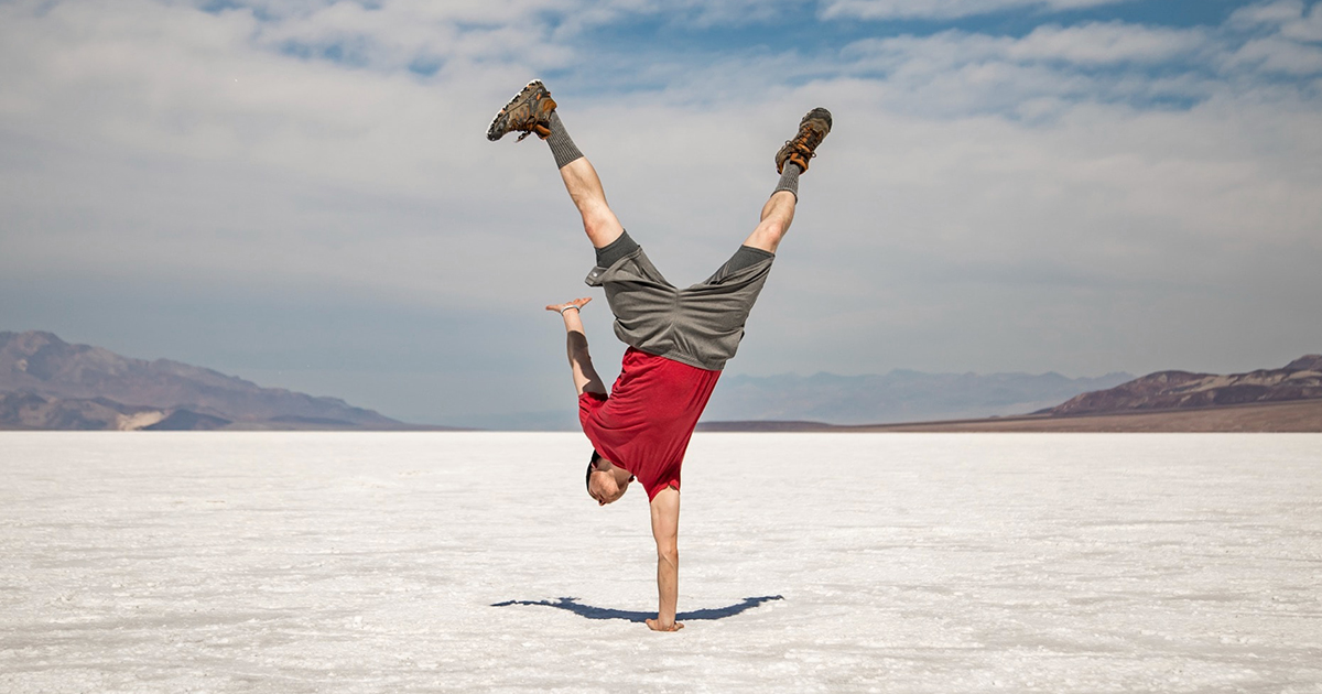 Person doing a one handed handstand in the desert