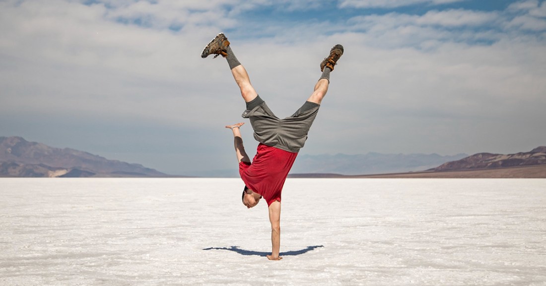 Person doing a one handed handstand in the desert