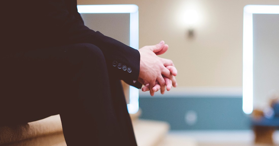 Man sitting with hands clasped on lap